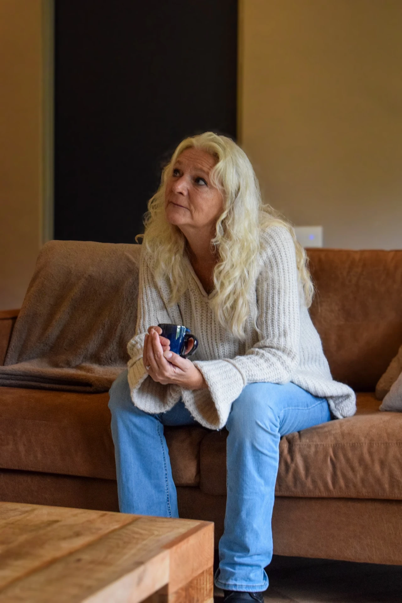 Vrouw met een kop koffie op de bank in haar woonkamer