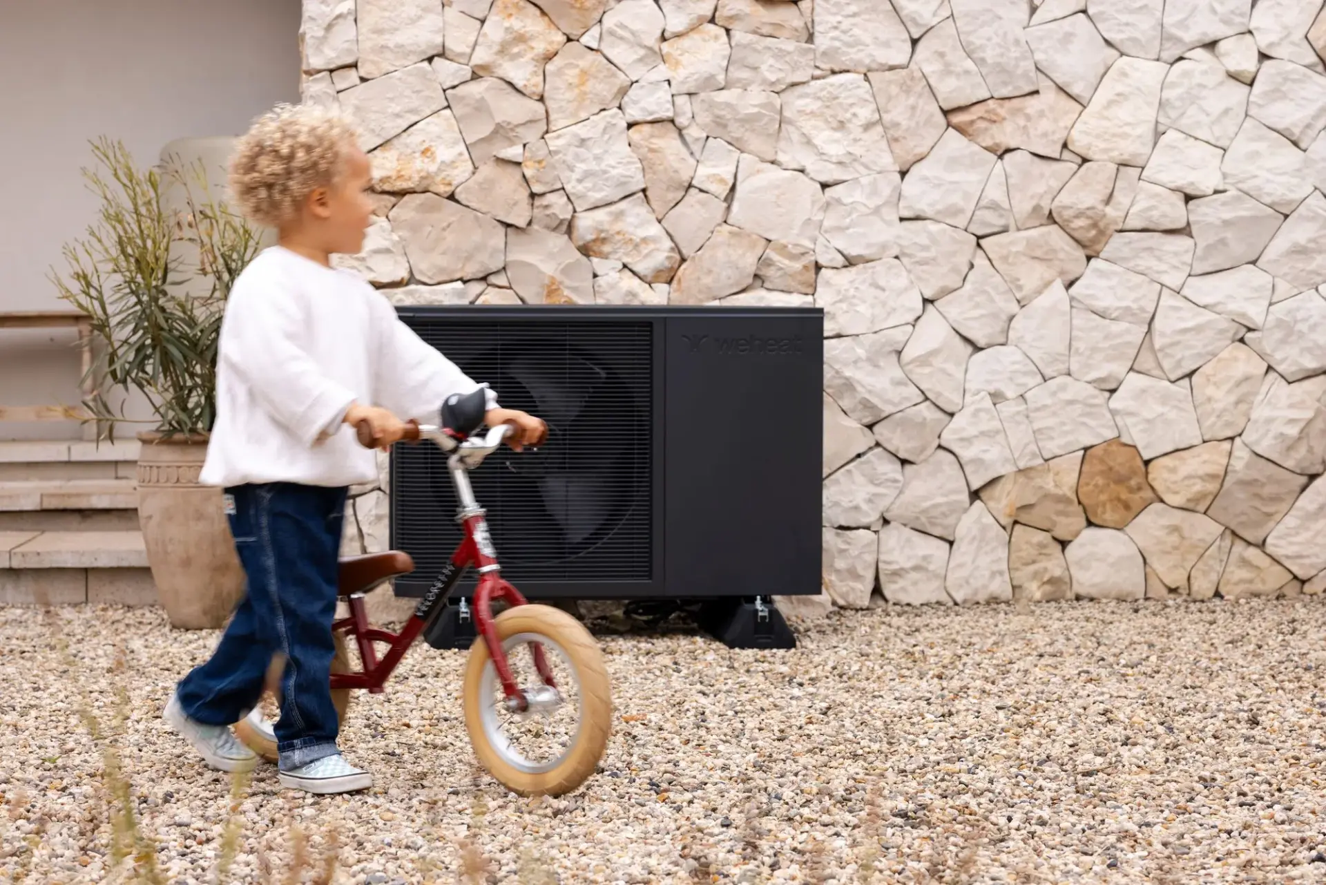 Kind met loopfiets voor een Weheat Flint warmtepomp